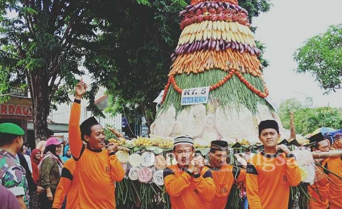 Ratusan masyarakat tumpah ruah ke jalan ikut mengarak tumpeng raksasa yang terdiri atas berbagai macam hasil bumi, Sabtu (28/12/2019)