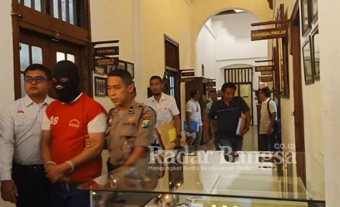 Kaos Merah tersangka saat di kawal petugas kepolisian