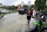 Kapolsek Glagah saat mengatur arus lalu lintas di jalan yang tergenang air dan masyarakat saat membersikan Enceng gondok.(IST)