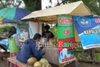 Adam, penjual es kelapa muda saat melayani pembeli, Rabu (14/04) [IST]