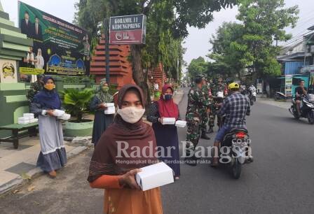 Anggota Koramil 0812/11 Kedungpring dengan membagi takjil kepada pengguna jalan yang melintas di depan Koramil 0812/11 kedungpring. Jumat (30/04)