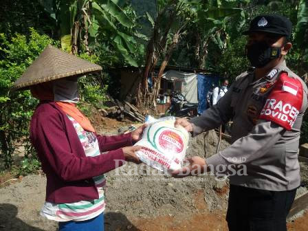 Bhabinkamtibmas desa Gelarwangi/Mekarjaya  Bribka Dede Hidayat di Kampung Cilemo desa Mekarjaya bersama Kapolsek Cidaun, sedang menyerahkan bantuan beras kepada KPM terdampak PPKM Level 4