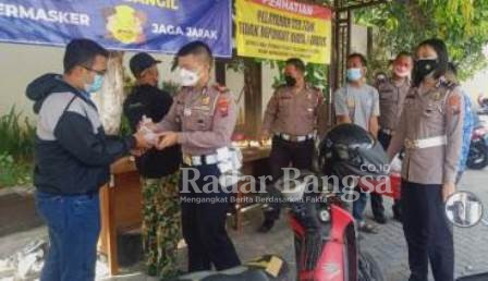 Kasat Lantas polres Pasuruan AKP. Andika Mizal Lubis.S.I.K, bersama kaur Reg Ident IPDA . Moneta Lestari saat memberikan makanan bergizi kepada salah satu wajib pajak