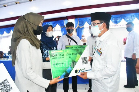  Bupati Cianjur H. Herman Suherman. ST. MAP sedang menyerahkan kartu peserta BPJS Ketenagakerjaan untuk UMKM pengrajin batik