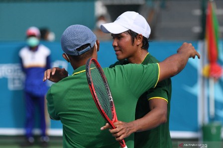 Petenis Jawa Timur M Fifqi Fitriadi (kanan) berpelukan dengan pelatihnya usai mengalahkan petenis Bengkulu Aditya Hari Sasongko dalam babak final tenis beregu putra PON Papua di Jayapura, Papua, Rabu (3/10/2021). ANTARA FOTO/Akbar Nugroho Gumay/tom.