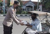 Kasat Binmas Iptu Turkhan Badri saat membagikan nasi kotak kepada tukang becak
