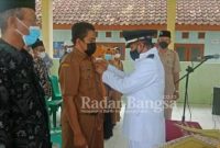 Pj. Kepala Desa Bugoharjo Kecamatan Pucuk Muzazin saat menyematkan lencana korpri ke Sekretaris Desa Moch Rahmat Shodik saat pelantikan berlangsung. Selasa (07/12). (Dok Foto: Istimewa Edi S./ RadarBangsa.co.id)