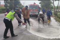Kasi Gakkum Satlantas Polres Lamongan Iptu Anang Purwoko dan anggota, petugas Damkar bersama warga gotong royong membersihkan cairan kimia disemprot air bercampur deterjen di jalan raya (IST)