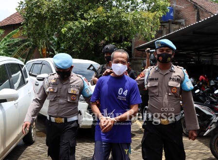 (Tengah) Dukun Cabul saat di kawal anggota Polisi (IST)