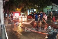 Petugas Damkar Bojonegoro saat membersihkan ceceran tanah di sepanjang Jalan Pemuda dan Jalan Basuki Rahmat Bojonegoro, Senin (13/6/2022). (Dok Foto KMF)