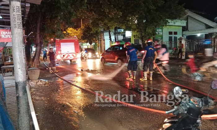 Petugas Damkar Bojonegoro saat membersihkan ceceran tanah di sepanjang Jalan Pemuda dan Jalan Basuki Rahmat Bojonegoro, Senin (13/6/2022). (Dok Foto KMF)