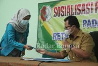 Koordinator Kebersihan dan Ruang Terbuka Hijau Dinas Lingkungan Hidup Kabupaten Bojonegoro Frika Deddy Sofyan menyerahkan virtual account kepada salah satu pengguna layanan QRIS, Selasa (7/6/2022) (Dok Foto IST)