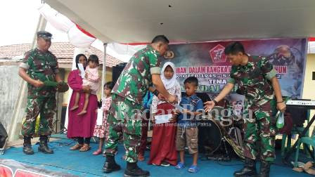 Danramil 0608 - 17/Cidaun Kapten Kav Ma'rufin didampingi oleh SERMA Asep Mulyana dan Dasep Kurnia sedang menyerahkan santunan anak yatim dalam acara Syukuran HUT TNI KE-77 dengan Tema 