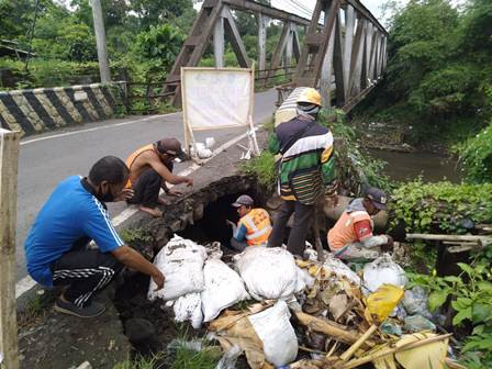 Pihak DPUTR Lumajang ketika melakukan pengurukan sementara di sisi timur jabatan penghubung 2 Kecamatan di desa Dawuhan Wetan. (IST)