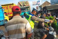 Ket Foto: Anggota Satlantas Polres Lumajang, Aiptu. Guntoro saat mengatur arus lalu lintas di pasar Wates wetan.