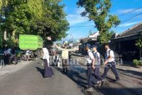 Anggota Polsek Pasirian ketika Menyeberangkan anak Sekolah didepan SMPN 1 Pasirian, Selasa (10/1/2023). (Dok Humas Polres, for Riyaman)