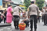 Kapolres Lumajang, AKBP. Dewa Putu Eka Darmawan, S.I.K., M.H, saat menyiram anggota yang naik pangkat, di halaman Mapolres Lumajang, Senin (2/1/2023) (Dok Humas Polres Lumajang)