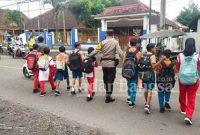 Ketika Anggota Polsek Pasirian Menyebrangkan anak sekolah SDN Pasirian 1, Kamis (16/2) (Dok Humas Polres Lumajang, for Riyaman)