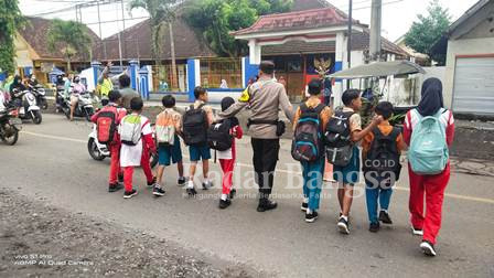 Ketika Anggota Polsek Pasirian Menyebrangkan anak sekolah SDN Pasirian 1, Kamis (16/2) (Dok Humas Polres Lumajang, for Riyaman)