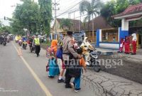 Anggota Polsek Pasirian saat Menyebrangkan siswa SDN Pasirian 1, Kamis (16/2). (Dok Humas Polres Lumajang, for Riyaman)