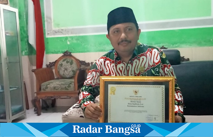 Kepala Desa Kaliboto Lor, Akhmad Fauzi, sedang memperlihatkan Piagam Penghargaan nya, ketika ditemui Radarbangsa.co.id di ruangan kerjanya, Selasa (27/6/2023). (Dok Riyaman/Radarbangsa.co.id).