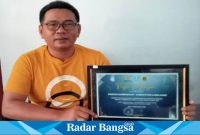 Kepala Desa Sumbersari, Adi Samaludin, saat menunjukkan piagam penghargaan PPID dari Provinsi Jatim, Jum'at (16/6). (Dok Riyaman/Radarbangsa.co.id).