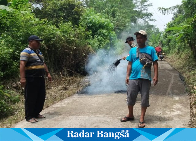 Kepala desa Girimukti Dodi Ahmadi (baju kaos belang-belang) sedang melakulan monitoring pembangunan peningkatan jalan desa dengan aspal lapen oleh UPTD PUPR Wilayah XI Cidaun. (Dok photo RadarBangsa.co.id/AE_Nasution)