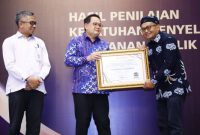 Ketua Ombudsman RI, M. Najih, saat menyerahkan penghargaan kepada Pj. Gubernur Jatim, Adhy Karyono, dalam acara penganugerahan di Hotel JW Marriott Surabaya, Jumat (13/12) (hms)