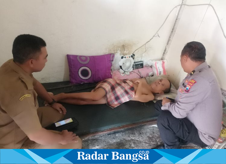 Kanit Binmas Polres Lamongan, Ipda Purnomo, bersama Kades Rudi saat melakukan kunjungan ke rumah Nur Rohman, seorang warga yang  sakit lumpuh (ist)