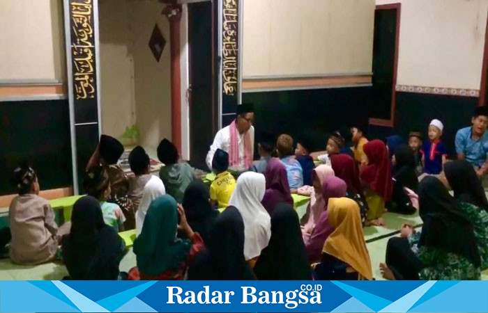 Aiptu Maryono membimbing puluhan anak santri membaca Al-Qur’an.(RadarBangsa.co.id).
