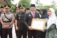 Bupati Sidoarjo Subandi menyerahkan penghargaan kepada guru dan siswa berprestasi di upacara Hardiknas 2025 di Alun-alun Sidoarjo. (ist)