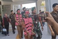 Dua tersangka kasus dugaan korupsi dana kompensasi jalan di Dusun Klayar, Desa Sidokelar, Kecamatan Paciran, saat digiring petugas Kejaksaan Negeri Lamongan menuju mobil tahanan, Selasa (22/7/2025).
