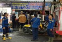 Petugas Damkar Lamongan bersama anggota Polsek Lamongan Kota saat memadamkan api yang membakar toko sembako Madura 24 Jam di Jalan KH Ahmad Dahlan, Kelurahan Jetis, Kamis malam (31/7/2025). (Foto Dok Ho/RadarBangsa)