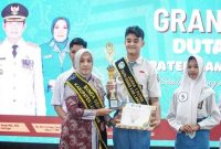 Bunda Genre Lamongan, Anis Kartika Yuhronur Efendi, menyerahkan trofi dan piagam penghargaan kepada Dimas Erlangga Putra Pratama yang terpilih sebagai Juara 1 Putra Duta Genre Lamongan 2025 pada grand final di Pendopo Lokatantra, Kamis (28/8/2025). (Foto Dok Ho/RadarBangsa.co.id)