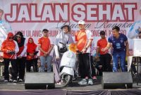 Bupati Lamongan Yuhronur Efendi saat menyerahkan hadiah utama berupa sepeda motor kepada peserta yang beruntung dalam jalan sehat peringatan HUT ke-80 RI di Kawasan Gadjah Mada, Sabtu (30/8/2025). (Foto Dok Ho/RadarBangsa.co.id)