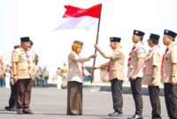 Khofifah menyerahkan bendera Merah Putih kepada Ketua Kwarnas Budi Waseso pada peringatan Hari Pramuka ke-63 di Surabaya, Kamis (14/8/2025). (Foto Dok Ho/RadarBangsa.co.id)