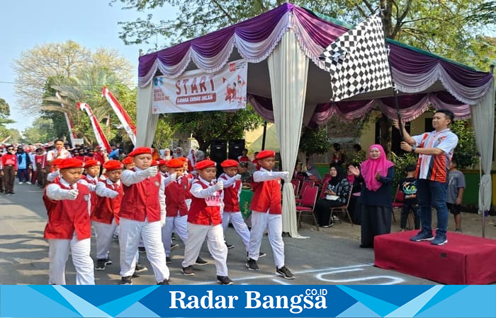 Ipda Andi Nurcahya melepas peserta lomba gerak jalan pelajar dari titik start di Lapangan Dusun Tikung, Desa Bakalanpule. (Foto Dok/RadarBangsa)