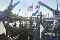 Personel Satpolairud Polres Lamongan membagikan bendera merah putih kepada nelayan di Pelabuhan Sedayulawas, Kecamatan Brondong, sebagai bagian peringatan HUT ke-80 Kemerdekaan RI, Senin (11/8/2025). (Foto Dok Ho/RadarBangsa.co.id)