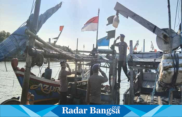Personel Satpolairud Polres Lamongan membagikan bendera merah putih kepada nelayan di Pelabuhan Sedayulawas, Kecamatan Brondong, sebagai bagian peringatan HUT ke-80 Kemerdekaan RI, Senin (11/8/2025). (Foto Dok Ho/RadarBangsa.co.id)
