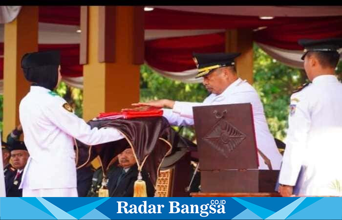 Bupati Madiun H. Hari Wuryanto menyerahkan bendera Merah Putih kepada anggota Paskibraka untuk dikibarkan pada upacara peringatan HUT ke-80 Kemerdekaan RI di Alun-Alun Reksogati, Caruban, Minggu (17/8/2025). (Foto Dok Ho/RadarBangsa.co.id)