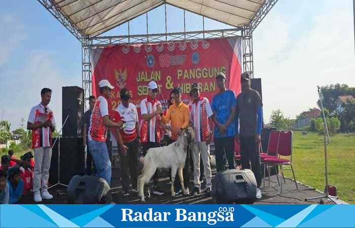 Wakil Bupati Lamongan Dirham Aksara menyerahkan hadiah utama berupa seekor kambing kepada perwakilan Desa Jatirejo, juara 1 lomba Kebersihan, Keindahan, dan Keamanan Lingkungan (K3L) tingkat Kecamatan Tikung, dalam acara Jalan Sehat HUT RI ke-80 di Lapangan Singo Ludro, Kamis (28/8/2025). (Foto Dok Ho/RadarBangsa.co.id)