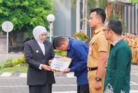 Gubernur Jawa Timur Khofifah Indar Parawansa menyerahkan bantuan secara simbolis kepada ASN Pemprov Jatim yang terdampak kebakaran Gedung Negara Grahadi saat apel bersama di Surabaya, Senin (8/9/2025) (Foto Dok Ho Adpim/RadarBangsa.co.id)