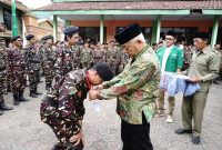 Seorang peserta SUSBALAN Banser Kabupaten Malang mencium tangan kiai sebagai simbol hormat dan khidmah dalam pembukaan kegiatan di Ponpes Mamba’ul Huda, Kecamatan Kasembon, Jumat (19/9). (RadarBangsa.co.id/Ho Prokopim Malang) 