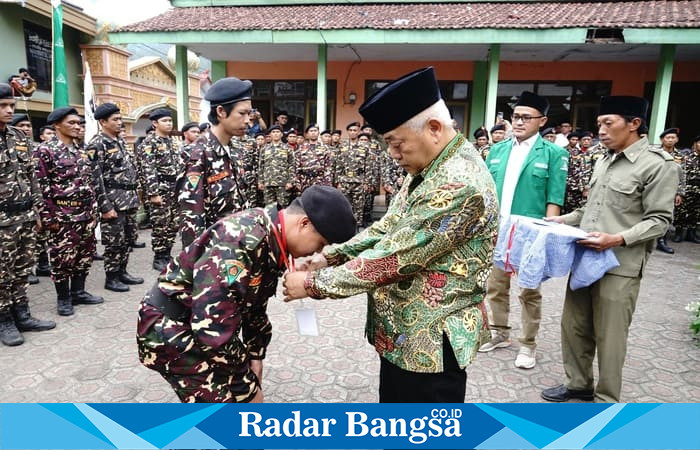 Seorang peserta SUSBALAN Banser Kabupaten Malang mencium tangan kiai sebagai simbol hormat dan khidmah dalam pembukaan kegiatan di Ponpes Mamba’ul Huda, Kecamatan Kasembon, Jumat (19/9). (RadarBangsa.co.id/Ho Prokopim Malang) 