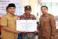 Bupati Bangkalan Lukman Hakim (kiri) menyerahkan secara simbolis bantuan sosial Program Penanggulangan Kemiskinan Ekstrem Tahun 2025 kepada salah satu penerima manfaat (tengah) di Kecamatan Geger, Senin (23/9/2025). (Foto Dok Ho/RadarBangsa.co.id)