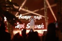 Seorang musisi tampil di panggung Festival Musik Tepi Sawah Banyuwangi 2025 dengan latar hamparan sawah dan pencahayaan artistik, Minggu (28/9/2025). (Foto Dok Ho/RadarBangsa.co.id)