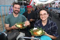 Dua wisatawan mancanegara menikmati sajian Sego Lemeng khas Suku Osing dalam Festival Sego Lemeng dan Kopi Uthek di Desa Banjar, Kecamatan Glagah, Banyuwangi, Sabtu (6/9/2025). (Foto Dok Ho/RadarBangsa.co.id)