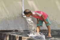 Seorang anak memanfaatkan aliran air dari pipa untuk minum di tengah musim kemarau. (Foto Dok Ho/RadarBangsa.co.id)