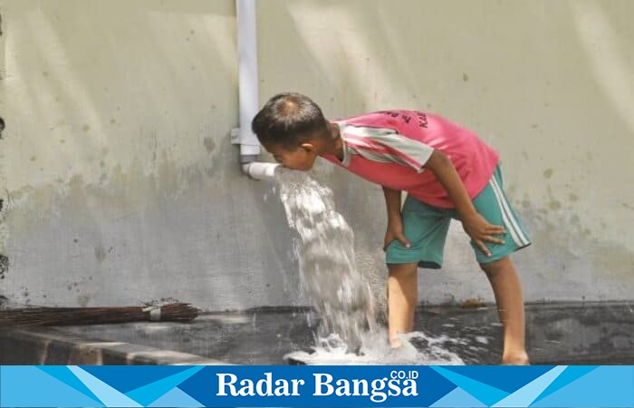 Seorang anak memanfaatkan aliran air dari pipa untuk minum di tengah musim kemarau. (Foto Dok Ho/RadarBangsa.co.id)