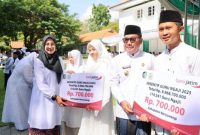 Bupati Banyuwangi Ipuk Fiestiandani menyerahkan secara simbolis insentif kepada guru ngaji saat upacara peringatan Hari Santri Nasional di halaman Kantor Bupati Banyuwangi, Rabu (22/10/2025). (Foto Dok Ho/RadarBangsa.co.id)